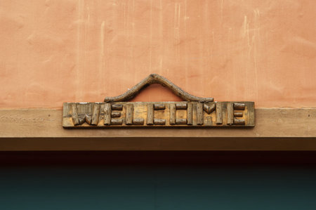Vintage handmade wooden welcome sign posted on brightly colored wall with copy space の写真素材
