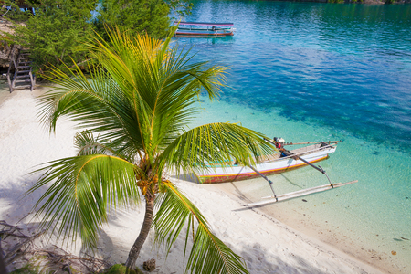 Photo Natural Wood Long Tail Boat Parked Caribbean Ocean Beach Island. Clear blue water. Horizontalの写真素材