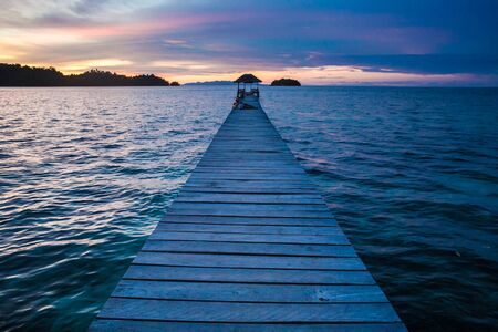 Photo Bungalow Pier in Indonesia Village Tropical Beach in Bali Island. Summer Season Caribbean ocean. Romantic View Point Sunset. Horizontal Pictureの写真素材