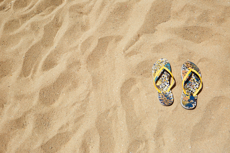 Closeup Beach Sandals Flip Flops or Tongs Sandy Beach Background Copyspace. Summer Concept. Horizontal. No body photoの写真素材