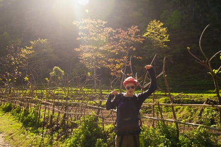Beautiful Woman Traveler Backpacker Mountains.Young Girl Posing Smiling Take Rest North Summer Landscape Background. Horizontal Photo.Sunlight Rays.Green Fieldsの写真素材