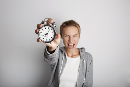 Portrait Handsome Young Woman Posing Blank White Background.Pretty Girl Screaming Holding Vintage Alarm Clock Hand Empty Wall.Beauty Lifestyle Fashion Hipster People.Wake Up Time Abstract Conceptの写真素材