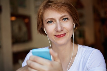 Closeup Portrait Fashionable Hipster Female Short Curly Hairstyle Wearing White Trendy Tshirt, Having Fun, Looking at the Camera with Mysterious Smile. Human Face Expressions and Emotionsの写真素材