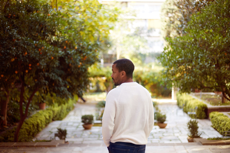 Portrait of Happy cute young African-American hipster in informal white jersey walking at sunny city park.Blurred backgroundの写真素材