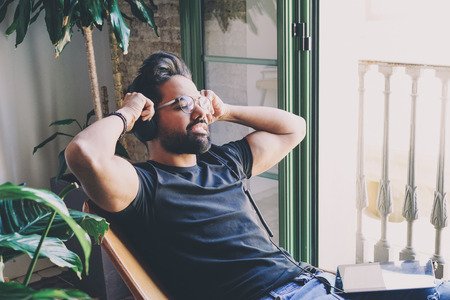 Handsome bearded man in headphones enjoy listening to music at home. Relaxing and rest time concept. Blurred background.の写真素材