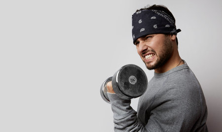 Young handsome man doing sport exercise on isolated empty background. Horizontal