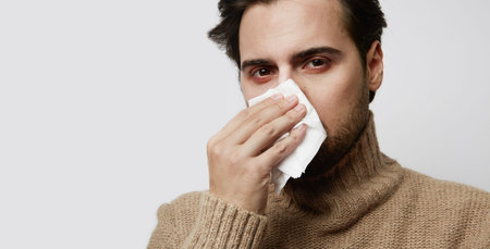 Portrait young bearded ill man wearing jersey coughing standing empty background