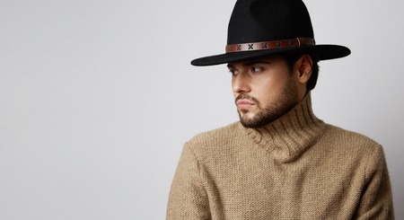 Portrait of a handsome caucasian man in hat wearing jersey isolated on white background. Copy paste space. Horizontalの写真素材