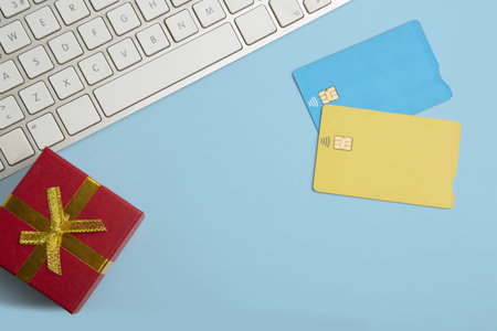 Mockup of two blank color credit cards, gift box on empty blue desk background. Business mock-up...
