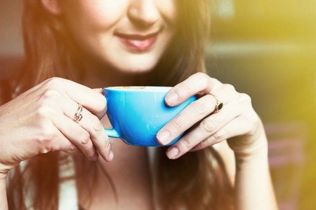 Portrait of smiling girl with cup of coffee at home. Visual effects. Blurred background.Croppedの写真素材