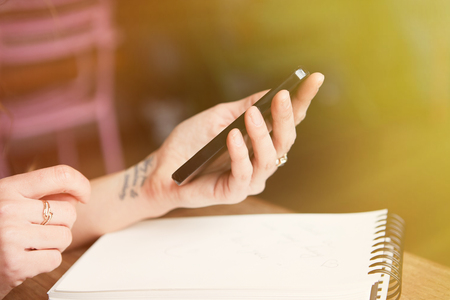 Closeup view of Charming young woman making notes and using mobile phone. Visual effects. Blurred backgroundの写真素材