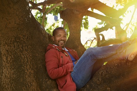 Attractive confident young African-American hipster in formal wear spending time at city garden park.Blurred backgroundの写真素材