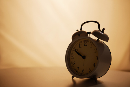 White vintage alarm clock on empty color background.の写真素材