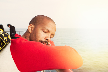 Handsome young African-American hipster man relaxing on the beach with closed eyes.Closeup portrait.の写真素材