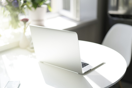 Work place at home. Laptop computer on the wooden table in light coloured living room of modern houseの写真素材