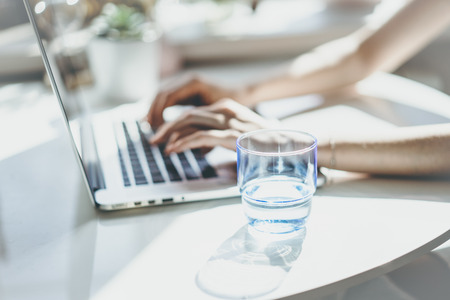 Beautiful business women pointing hand on a laptop computer while sitting at the wooden table in light coloured living room of modern house.の写真素材