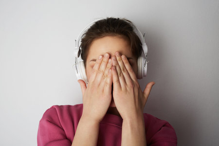 Fashion pretty cool girl in white headphones listening to music wearing colorful pink hoody over...
