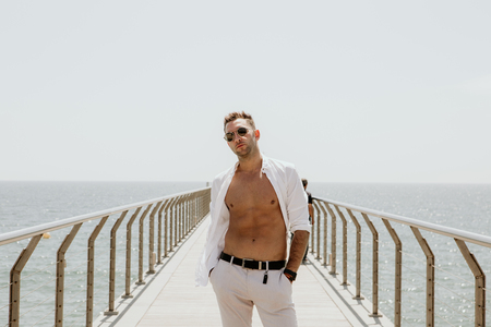 Handsome happy man wearing white shirt and sunglasses at the sea or the ocean background.Travel vacation holiday conceptの写真素材