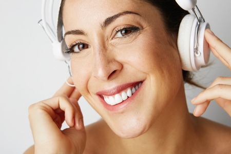 Portrait of fashion happy cool girl stripped to the waist in white headphones listening to music over empty white background. Relaxing and enjoying concept.Closeupの写真素材