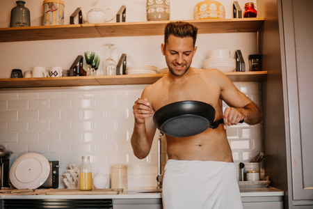 Sexy chef with naked body cooking in the home kitchenの写真素材
