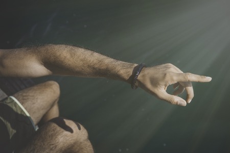 Man pointing male hand on seaside and looking into the distance on the horizon in the sea. Sunlight effects on backgroundの写真素材