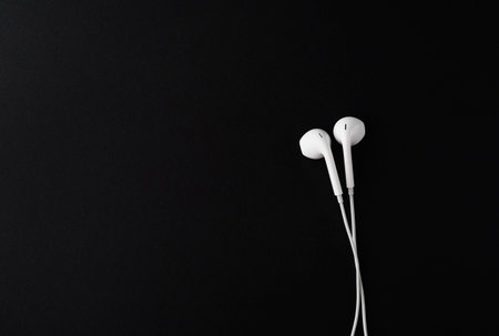 Top view of White Earbuds or Earphones on black background. Copy paste space