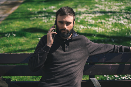 Bearded man using mobile smartphone outside. Blurred backgroundの写真素材