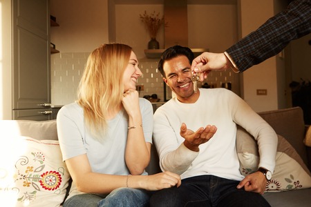 Happy smiling young couple showing a keys of their new house.の写真素材