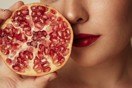 Beauty woman with orange pomegranate cut in half over white background. Attractive fresh vitamin concept.Closeup shot.の写真素材