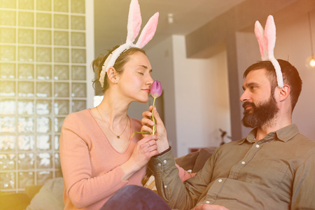 Bearded man gives a one flower a tulip to his Beautiful girlfriend. Happy family preparing for Easterの写真素材