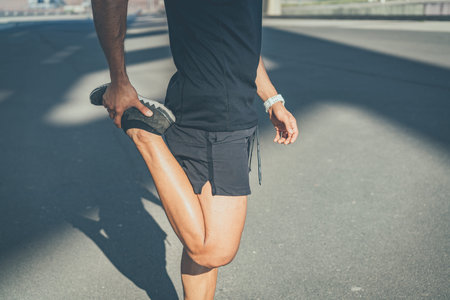 Muscular Male athlete sprinter doing stretching exercise, exercising outdoors, jogging outside....