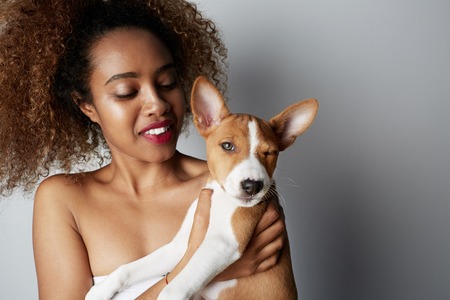 Handsome black american african girl embracing puppy on white background. Studio portrait of white appealing female chilling with dog on white backgroundの写真素材