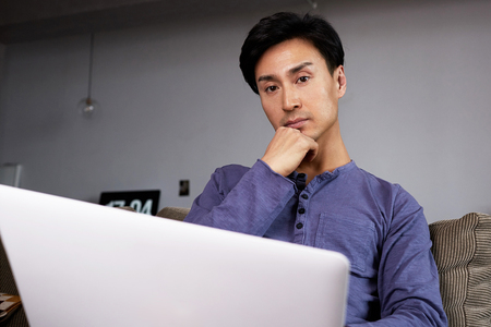 Asian Man Working Laptop Home Connecting Networking Concept.の写真素材
