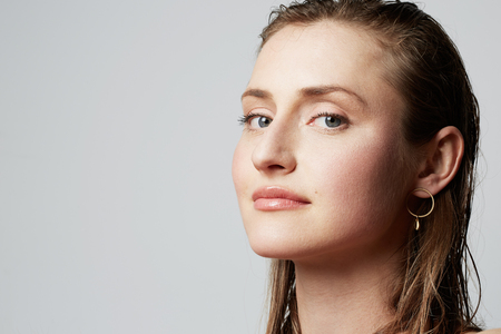Beauty portrait of a smiling young female with natural makeup over white background. Cosmetology and Advertisement.の写真素材