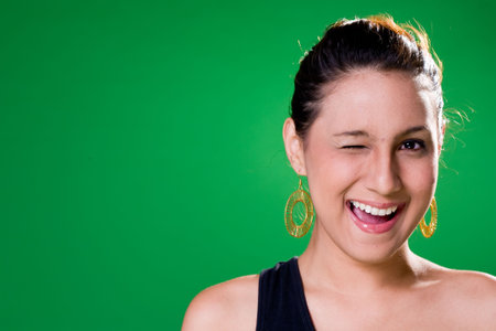 expressive young woman on green background with one eye closedの写真素材