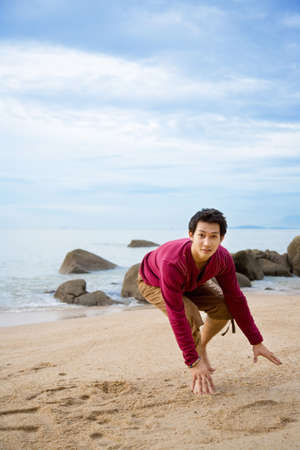 a man running half squat on the beachの写真素材