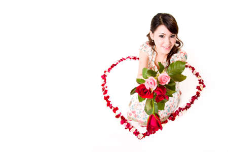 young woman with roses sitting inside a heart shaped made of rose petalsの写真素材