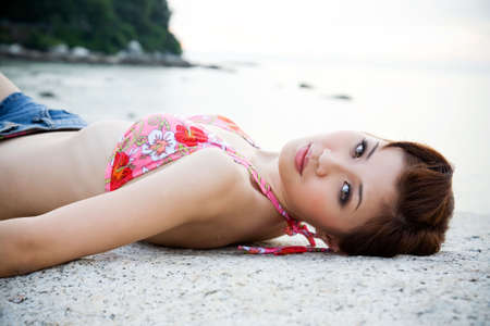 woman lying on the sunset beach with bikini topの写真素材