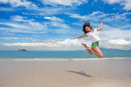 young beautiful girl jumping gracefully at the beachの写真素材