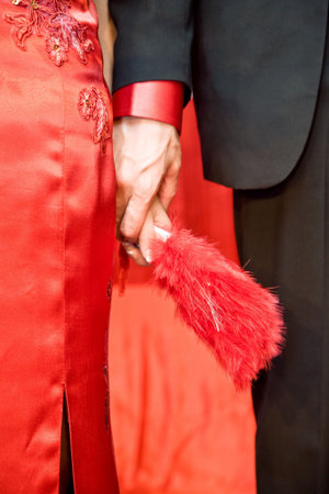 newly wed asian chinese bride in traditional red cheongsam dress holding hands with the groom on their weddingの写真素材
