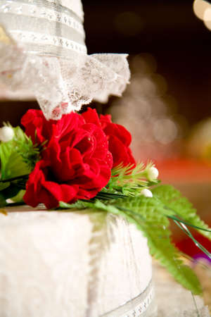 layered wedding cake with red floral decorationの写真素材