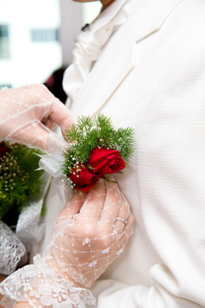 bride put on red roses crochet onto the grooms coat