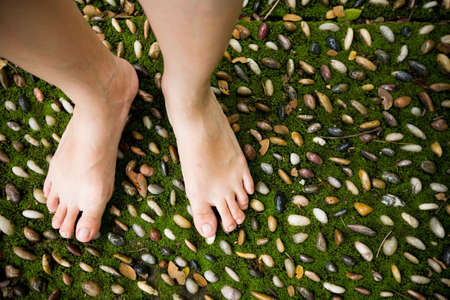 female bare feet stepping on therapy stones の写真素材