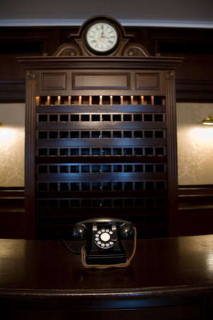 old vintage hotel lobby desk with telephone and clock and key shelfの写真素材
