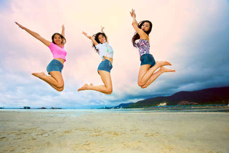 group of happy asian woman jumping up high at the beachの写真素材