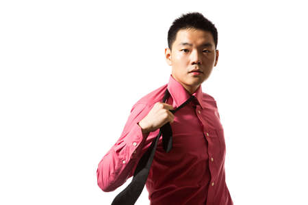 stylish asian young man in pink shirt untying black tieの写真素材