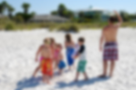 Blur of a group of kids with their father playing on the beachの写真素材
