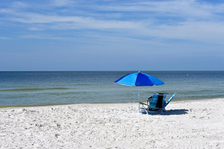 Beach Umbrella and Two Chairs on the Beach with the ocean and sky in the backgroundの写真素材