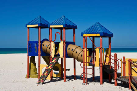 Kids Playground Equipment on a Sandy Beach with Ocean Backgroundの写真素材