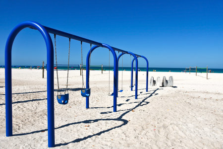 A Large Blue Metal Swing Set on a Sandy Beachの写真素材
